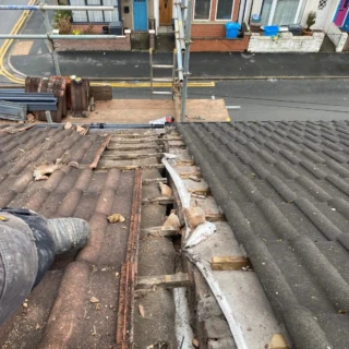 View from roof scaffolding showing stripped tiles and timber battens along a party wall valley in Hull.
