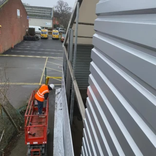 Commercial contractor on a scissor lift installing external wall cladding on a steel building frame in Hull.